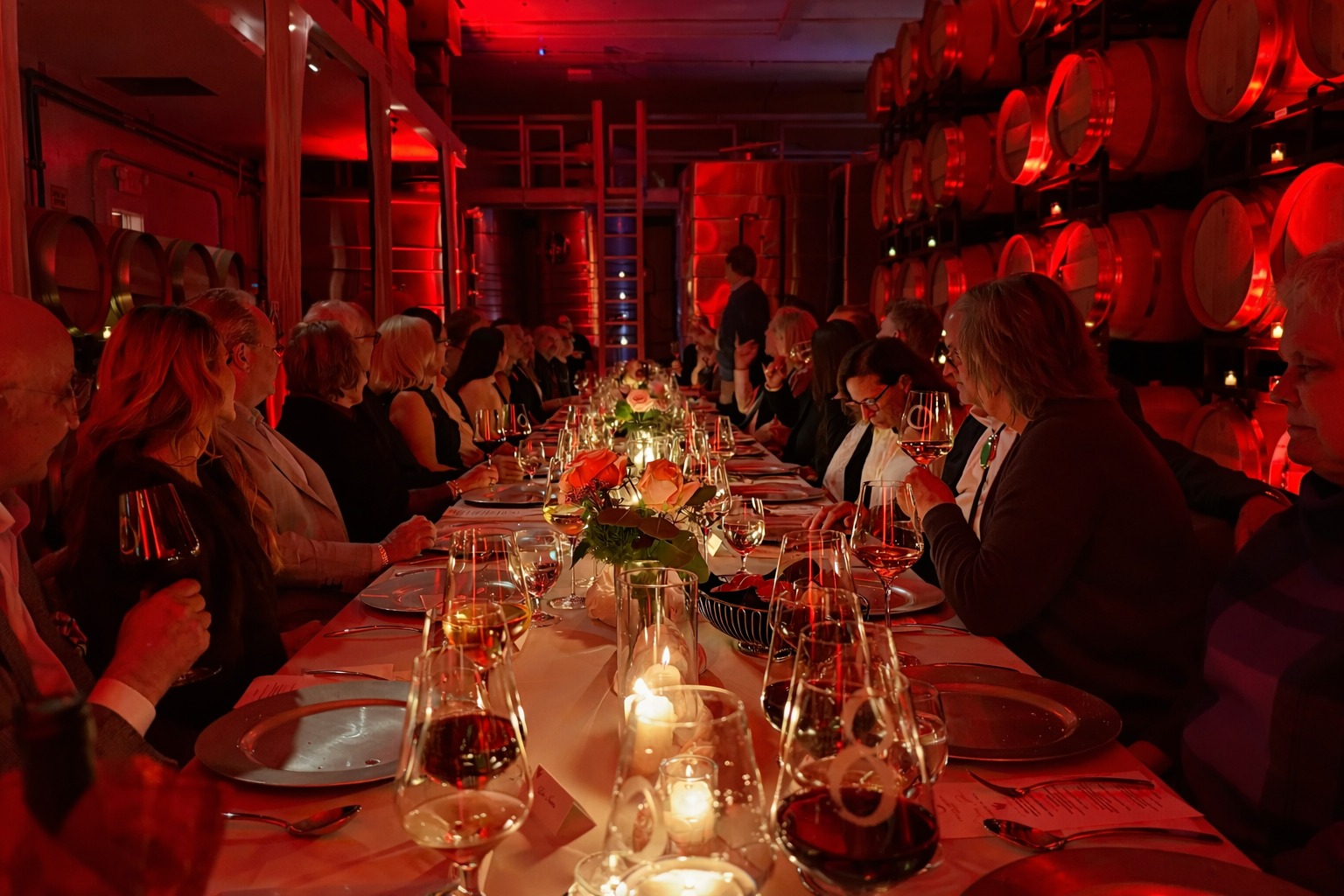 Guests dining at a long candlelit table in the barrel room
